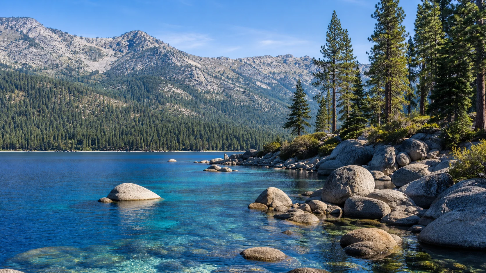 Clear blue Lake Tahoe water, granite boulders, pine trees, and Sierra mountains